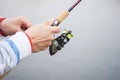 A fisherman catches a fish. Hands of a fisherman with a spinning rod in hand closeup. Spin fishing reel Royalty Free Stock Photo