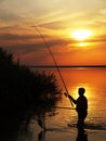 Fisherman catches fish by spinning on the lake at sunset