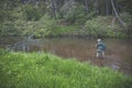 A fisherman releases a small trout into the stream