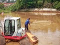 Tangerang, Indonesia, August 2022, a fisherman catching fish in the murky water of a lake being dredged by an excavator