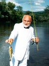 Fisherman caught a trout fish. Portrait of cheerful senior man fishing. Grandfather with catch fish. Mature man Royalty Free Stock Photo