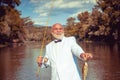 Fisherman caught a trout fish. Portrait of cheerful smiling angler senior man fishing. Grandfather with catch fish Royalty Free Stock Photo