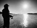 Fisherman check fishing line and pushing bait on the rod. Fisherman silhouette at sunset Royalty Free Stock Photo