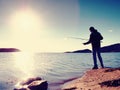 Fisherman check fishing line and pushing bait on the rod, prepare himself and throw lure far into peaceful water. Royalty Free Stock Photo