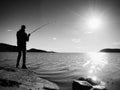 Fisherman check fishing line and pushing bait on the rod, prepare himself and throw lure far into peaceful water. Royalty Free Stock Photo