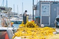 Fisherman checks and mends bright yellow fishing nets on wharf