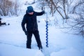 A fisherman drills a hole in the ice to catch fish, Tom river in Kemerovo, Russia Royalty Free Stock Photo