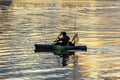 fisherman in early morning light fishes with his canoe at river colorado with golden sunrise reflections Royalty Free Stock Photo