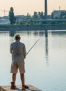 Fisherman at the edge of a lake in Bucharest, holding a fishing rod. Man fishing