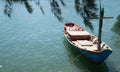 Fisherman fishing boat anchored at pier under pine tree with natural blue green seawater background. marine vessel, occupational t Royalty Free Stock Photo