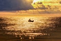 Fisherman with fishing boat sailing on golden sea Royalty Free Stock Photo