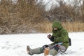 A fisherman is fishing in an ice hole on a frozen pond.
