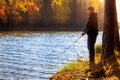 Fisherman fishing in the lake from shore on sunny autumn day Royalty Free Stock Photo