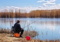 A fisherman with a fishing rod sitting on a chair