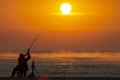 Fisherman fishing in the Sea or Ocean beach during sunrise. Swinging a rod Royalty Free Stock Photo