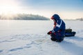 A fisherman is fishing with a winter spinning rod on a frozen lake Royalty Free Stock Photo