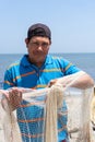 Fisherman fixing his fishing net with rope. Fisherman doing maintenance on his work equipment