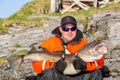 Fisherman in glasses holding big fish on his hands. Smiling Royalty Free Stock Photo