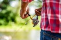 Fisherman hand holding fishing rod with reel. Fishing Reel. Fishing rod with aluminum body spool. Fish Supplies and Royalty Free Stock Photo