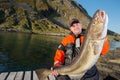 Fisherman happy man holding a huge fish Cod. Pier. horizontal po