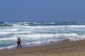 Fisherman in helmet looking like astronaut standing and fishing on the beach next to the sea