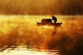 Fisherman and his boat in a misty morning with golden sunlight Royalty Free Stock Photo