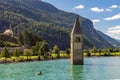 Fisherman in his boat near the submerged bell tower in Resia lake, Curon, South Tyrol, Italy Royalty Free Stock Photo