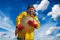 Fisherman Holding a Big Fish Against Blue Sky and Clouds Royalty Free Stock Photo