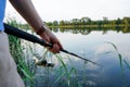 Fisherman holding fishing rod at the lake. Fishing. Closeup of hand holding fishing rod and fishing reel. Royalty Free Stock Photo