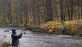 A fisherman holding a fishing rod and turning a reel handle. A man catches fish in a mountain river Royalty Free Stock Photo