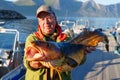 Fisherman holding a huge fish Cod. Norway Fishing tourism. Senior fisherman in ocean, fjord fishing. Royalty Free Stock Photo