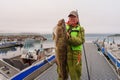 Fisherman holding a huge fish Cod. Norway Fishing tourism. Senior fisherman in ocean, fjord fishing. Royalty Free Stock Photo