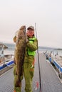 Fisherman holding a huge fish Cod. Norway Fishing tourism. Senior fisherman in ocean, fjord fishing. Royalty Free Stock Photo