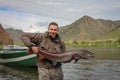 A fisherman holding a huge Taimen trout caught on a river in Mongolia, Moron, Mongolia