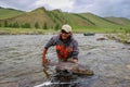 A fisherman holding a huge Taimen trout caught on a river in Mongolia, Moron, Mongolia - July 14th 2014