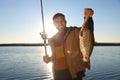 Fisherman holding rod and catch at riverside, focus on fish Royalty Free Stock Photo