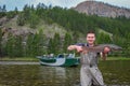 A fisherman holding a taimen trout caught on a river in Mongolia, Moron, Mongolia