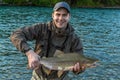 A fisherman holding up a large pink `humpback` salmon at sunset Royalty Free Stock Photo