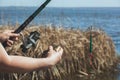 The fisherman holds in his hands caught fish and a rod with a reel against the background of the river Royalty Free Stock Photo