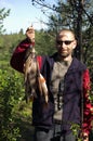 Fisherman holds some graylings and perches.