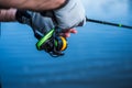 The fisherman holds a spinning rod in his hands. Angler with spinning rod and fishing reel. Hands and spinning on the background Royalty Free Stock Photo