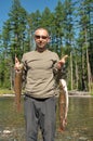 Fisherman holds up two large fish. Royalty Free Stock Photo