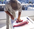 Fisherman with knife prepares tuna for eating after fishing Royalty Free Stock Photo