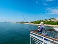 Fisherman on the bridge with a pier and jumping and walking people in Burgas, Bulgaria