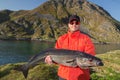 Fisherman Man in glasses holding big fish Cod Royalty Free Stock Photo