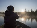 Fisherman man in rowing boat at lake Sjabatjakjaure in Beautiful sunny morning haze mist in Sweden Lapland nature. Mountains,