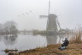 Fisherman at the misty and calm windmill sunrise Royalty Free Stock Photo