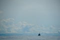 Fisherman motor boat sailing independently in vast ocean on light sea wave with white cloud and blue sky background Royalty Free Stock Photo