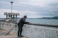 A fisherman overlooking the sea. Fishing rods resting on the side waiting for fish. Fisherman on a sea bridge. Royalty Free Stock Photo