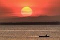 Fisherman paddling with sunset background